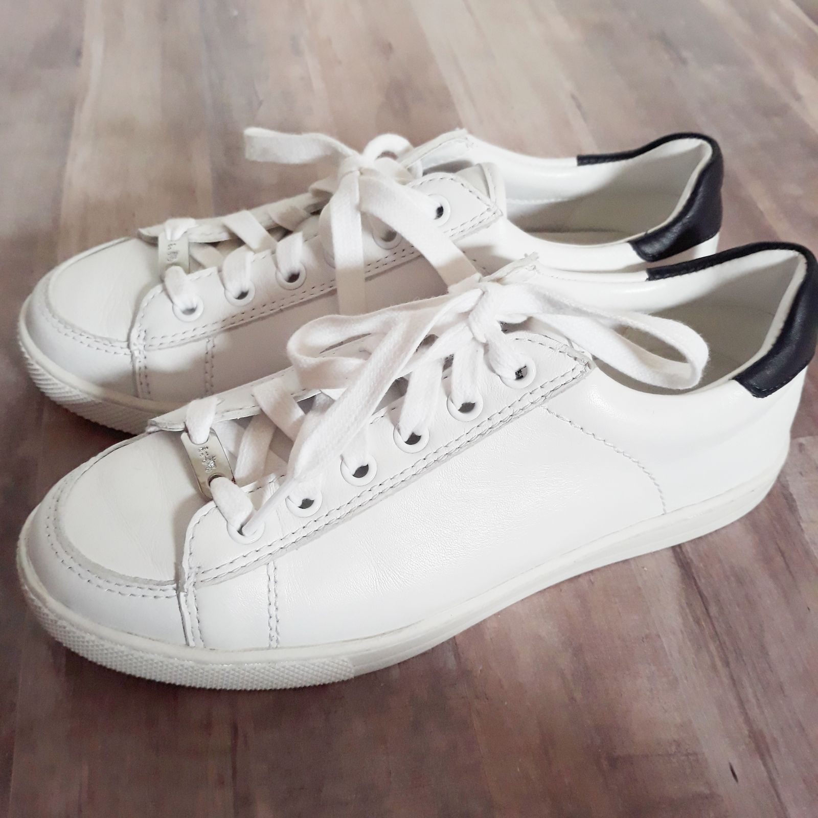 White leather tennis shoes by Coach. Features black heels and silver ...